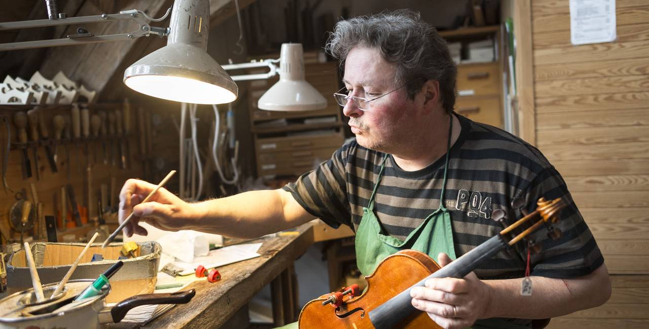 Geigenbauer bei der Arbeit in der Werkstatt.